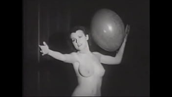 Erotic retro model with a beautiful figure plays with balloons for the crowd on stage